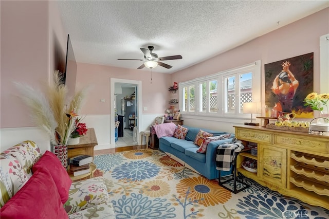 living room with ceiling fan and a textured ceiling