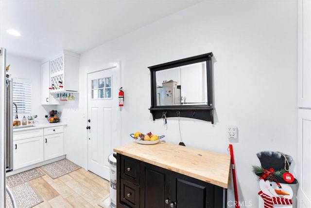 817 E Palmyra Ave, Orange, CA 92866 - kitchen featuring dark cabinetry, white cabinets, light wood finished floors, freestanding refrigerator, and butcher block counters