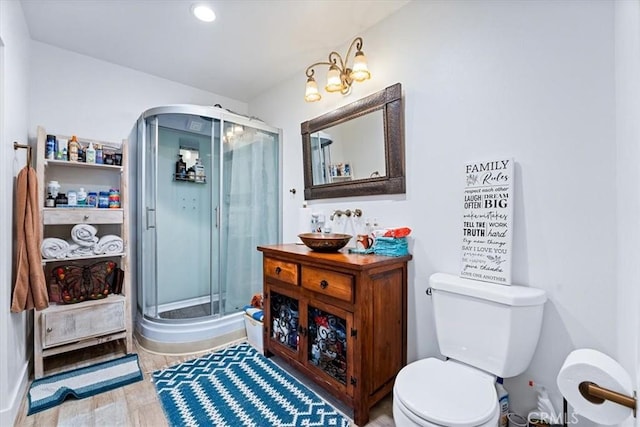 bathroom with sink, hardwood / wood-style flooring, a shower with door, and toilet