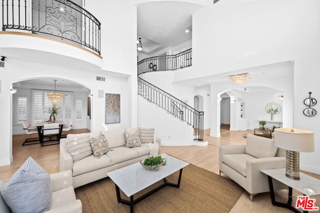 living room with light hardwood / wood-style floors, a high ceiling, and an inviting chandelier