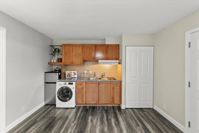 interior space with sink, dark hardwood / wood-style flooring, washer / dryer, backsplash, and stainless steel refrigerator