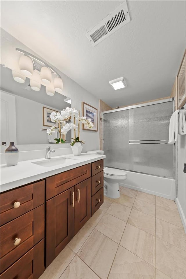 full bathroom with tile flooring, toilet, vanity, and combined bath / shower with glass door