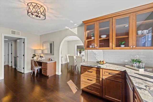 bar with tasteful backsplash, light stone counters, hanging light fixtures, dark wood-type flooring, and an inviting chandelier