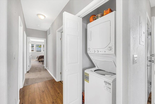 laundry area with stacked washer / dryer and light colored carpet