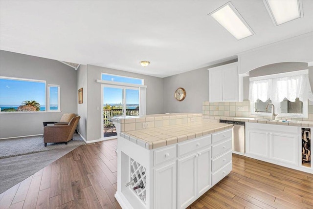 kitchen featuring dishwasher, light wood-type flooring, sink, and tile countertops