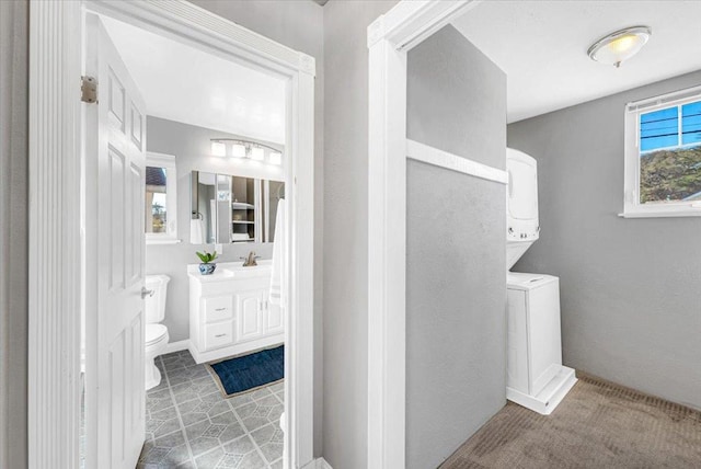 bathroom featuring tile patterned floors, vanity, stacked washer and clothes dryer, and toilet