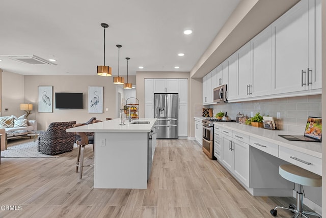 kitchen featuring stainless steel appliances, decorative light fixtures, a kitchen bar, tasteful backsplash, and white cabinets