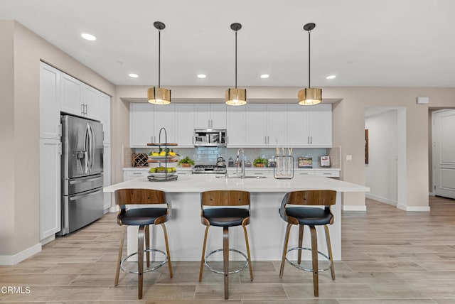 kitchen with backsplash, hanging light fixtures, stainless steel appliances, and a center island with sink