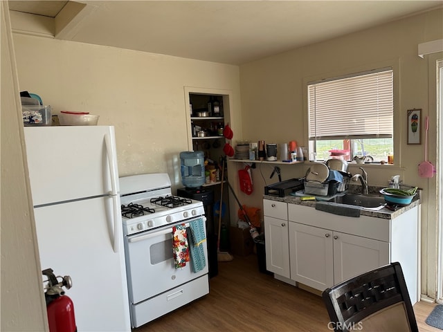 kitchen featuring white appliances, white cabinets, hardwood / wood-style floors, and sink