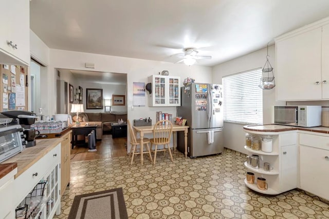 kitchen with white cabinetry, stainless steel refrigerator, ceiling fan, and light tile floors