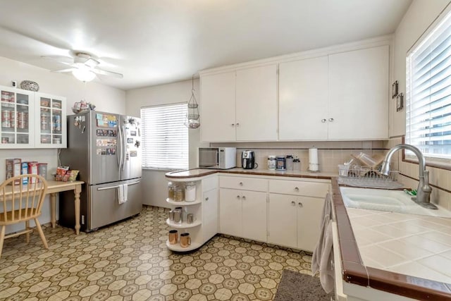 kitchen with stainless steel fridge, ceiling fan, sink, a wealth of natural light, and white cabinets