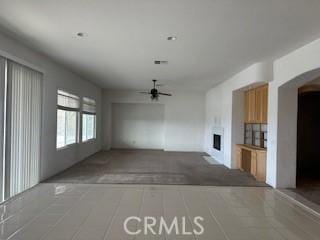 unfurnished living room with ceiling fan