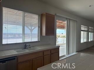 kitchen with tile counters, dishwasher, and sink