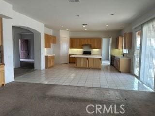 kitchen featuring light tile patterned floors, a kitchen island, and exhaust hood