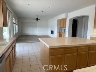 kitchen featuring ceiling fan, dishwasher, a kitchen island, and light tile patterned flooring