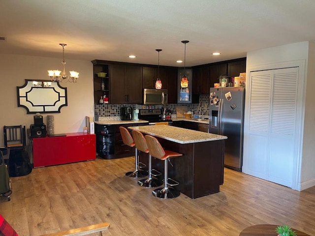 kitchen featuring decorative backsplash, pendant lighting, appliances with stainless steel finishes, and dark brown cabinets