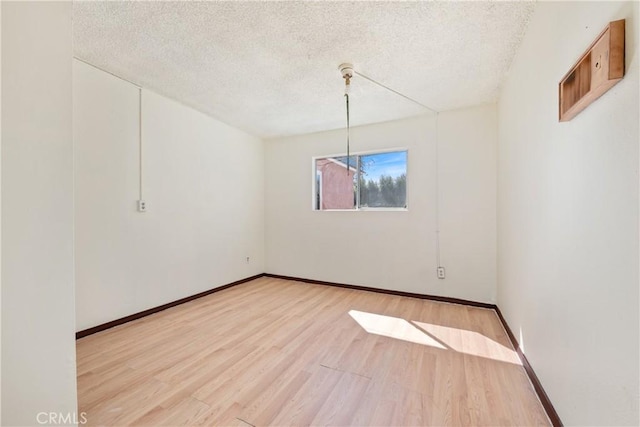 empty room featuring baseboards, wood finished floors, and a textured ceiling