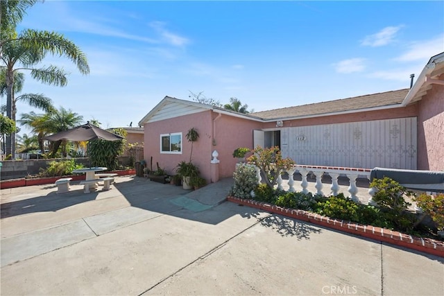 view of side of home with fence, a patio area, and stucco siding