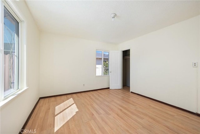 unfurnished bedroom featuring baseboards, light wood-style floors, and a closet