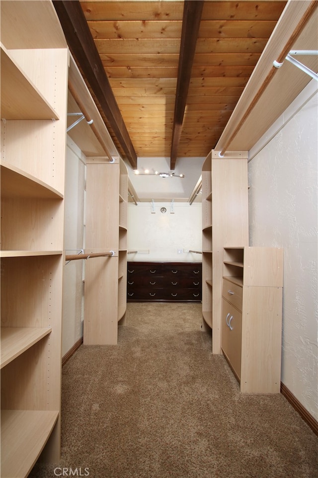 walk in closet with beam ceiling and carpet floors