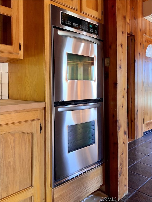 kitchen featuring double oven and wood walls