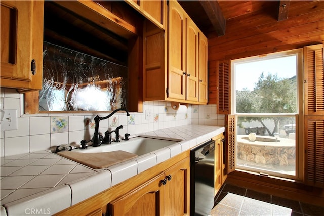 kitchen featuring backsplash, dark tile patterned flooring, black dishwasher, beamed ceiling, and tile counters