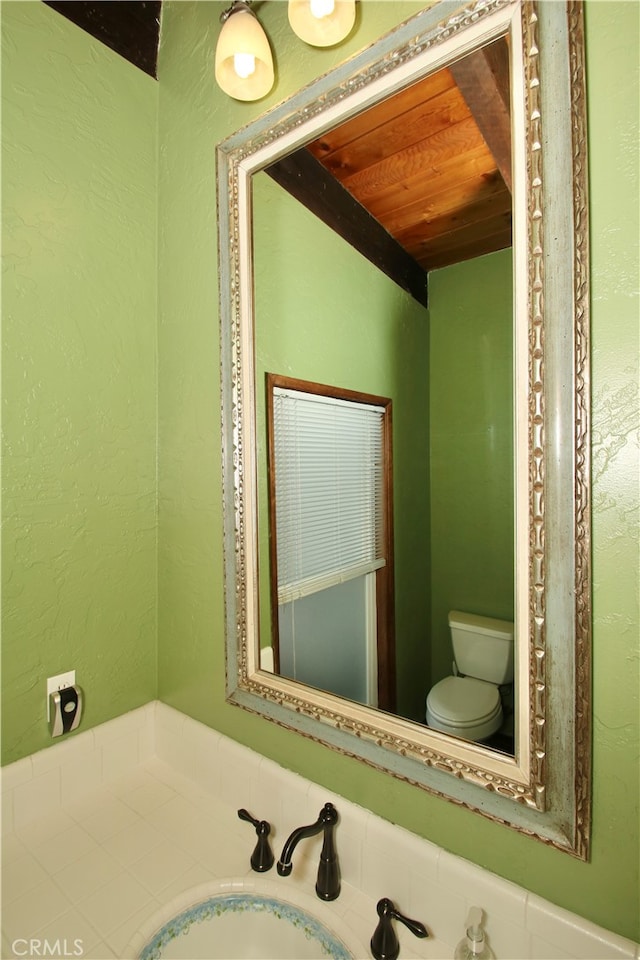 bathroom with toilet, wooden ceiling, and sink