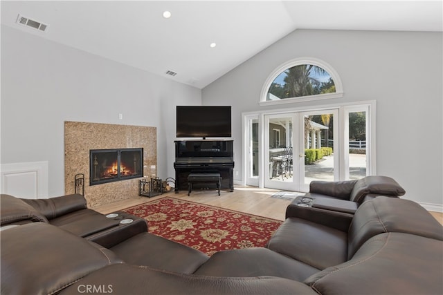 living room with high vaulted ceiling, light wood-type flooring, and french doors