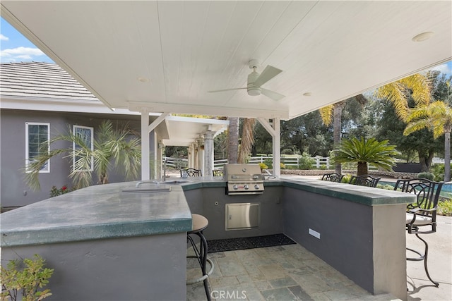 view of terrace featuring grilling area, a bar, an outdoor kitchen, and ceiling fan