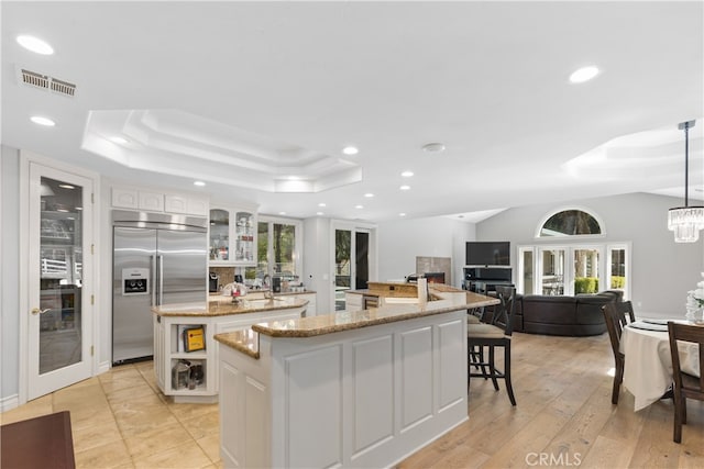 kitchen with pendant lighting, built in fridge, an inviting chandelier, white cabinetry, and a center island