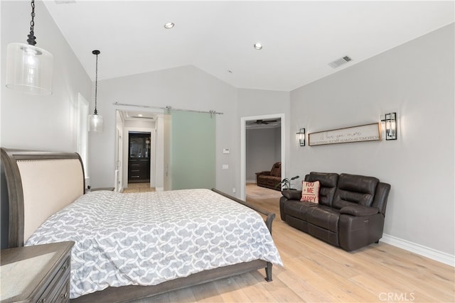 bedroom featuring a closet, a walk in closet, vaulted ceiling, and light hardwood / wood-style flooring