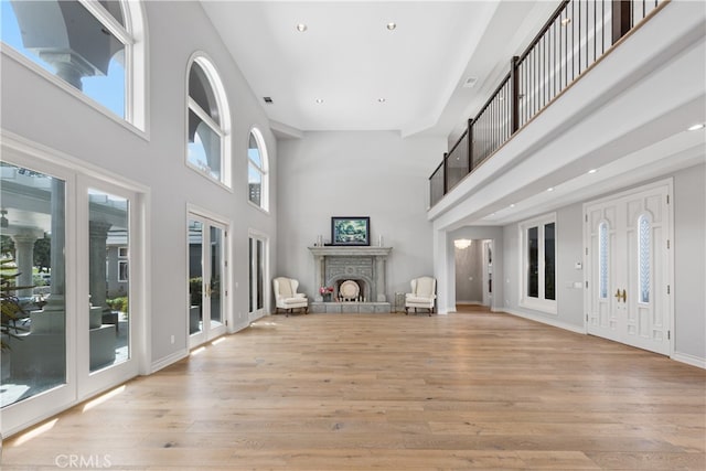 unfurnished living room with light wood-type flooring and a high ceiling