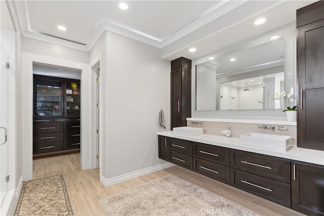 bathroom with backsplash, hardwood / wood-style flooring, ornamental molding, and vanity