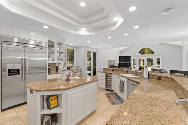 kitchen featuring a center island with sink, stainless steel appliances, white cabinets, and light stone countertops