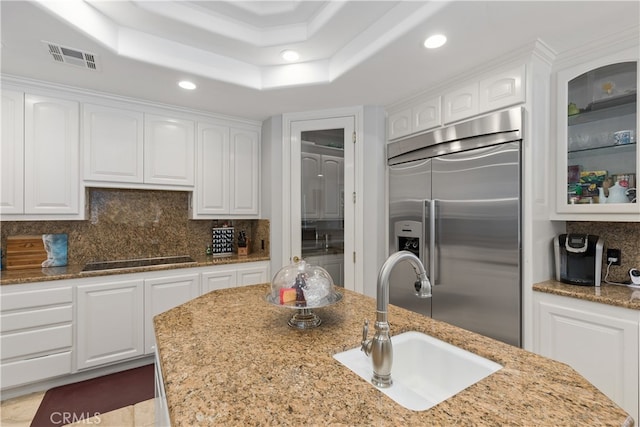 kitchen with built in fridge, tasteful backsplash, and white cabinets