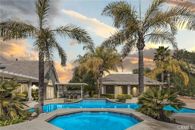 pool at dusk with a patio area