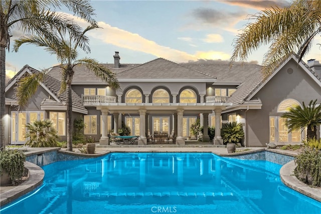 pool at dusk featuring a patio