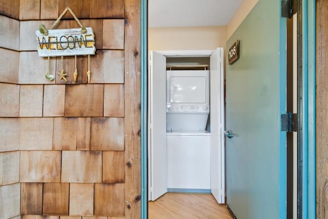 hallway with stacked washer and clothes dryer and hardwood / wood-style floors