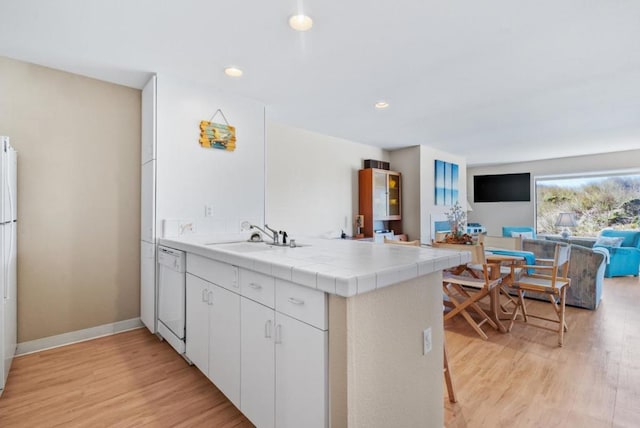 kitchen featuring dishwasher, tile countertops, kitchen peninsula, sink, and white cabinets