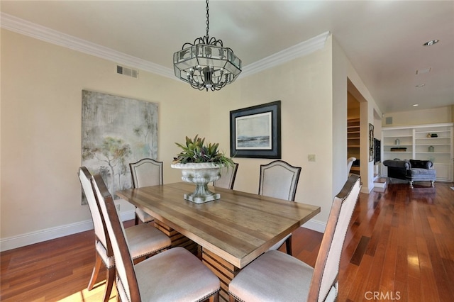 dining space featuring crown molding, dark hardwood / wood-style floors, an inviting chandelier, and built in shelves