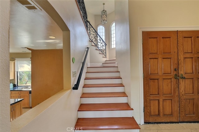 staircase featuring light tile flooring, sink, and a wealth of natural light