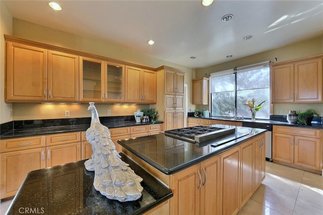 kitchen featuring stainless steel appliances, dark stone counters, light tile floors, and a center island