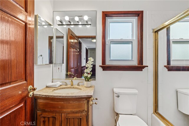 full bathroom with shower / bath combination with glass door, vanity, and toilet