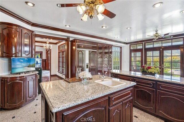 kitchen featuring french doors, ornamental molding, sink, a center island with sink, and an inviting chandelier