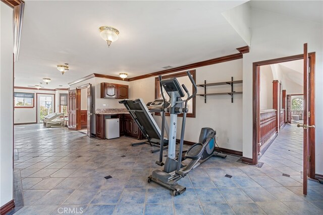 exercise room with ornamental molding and light tile patterned flooring