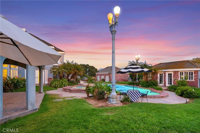 pool at dusk featuring a lawn