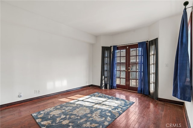 empty room with dark hardwood / wood-style flooring and french doors