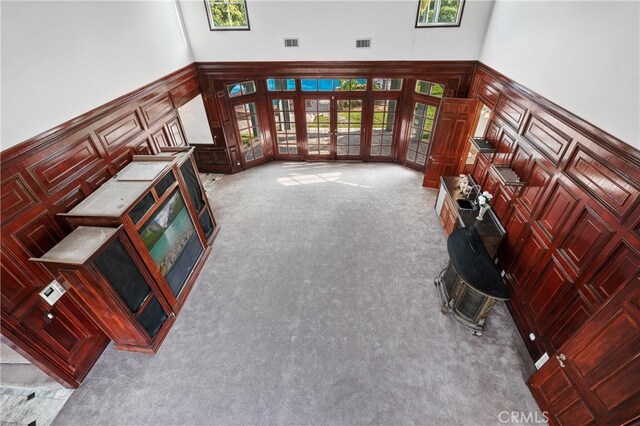 unfurnished living room featuring light carpet, french doors, and a towering ceiling