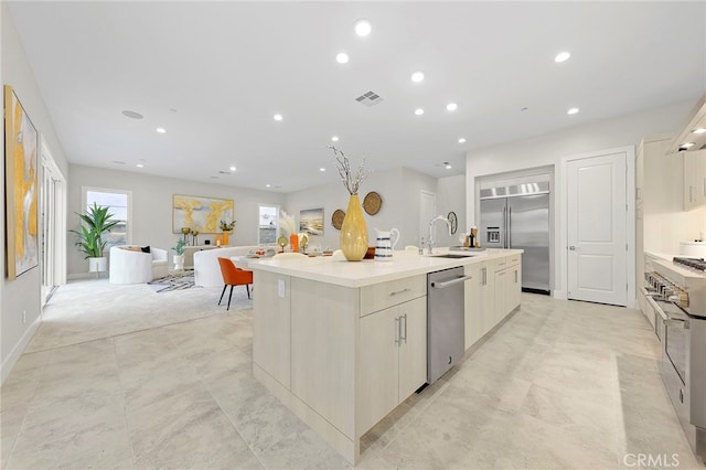 kitchen featuring light tile floors, appliances with stainless steel finishes, sink, and a kitchen island with sink