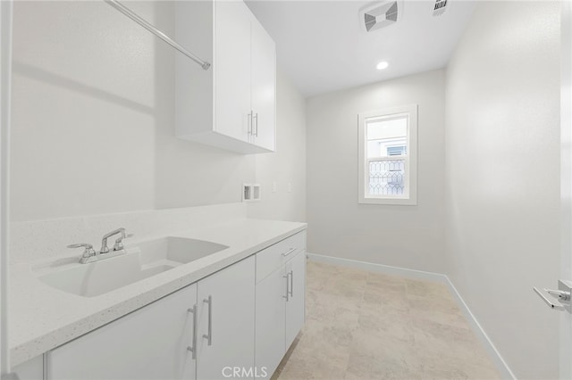 interior space with washer hookup, cabinets, light tile flooring, and sink